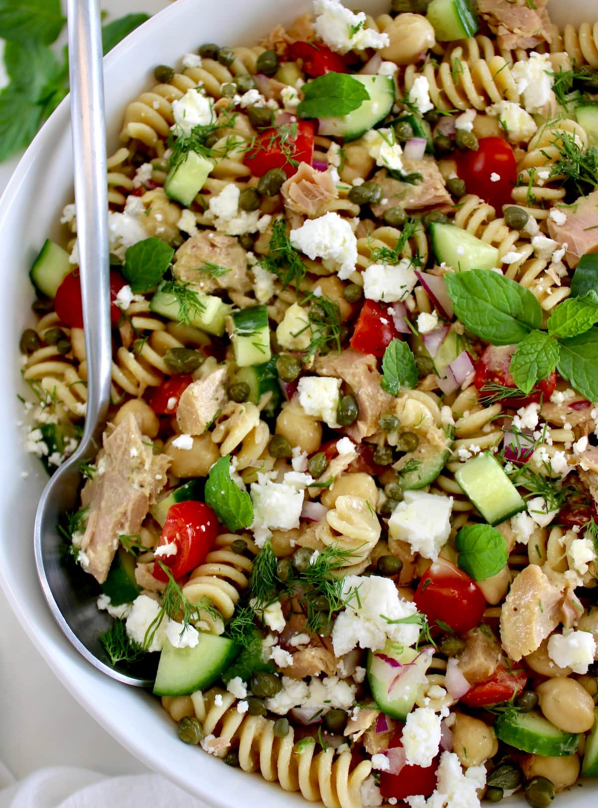 closeup of Chickpea Tuna Pasta Salad in white bowl with spoon on side