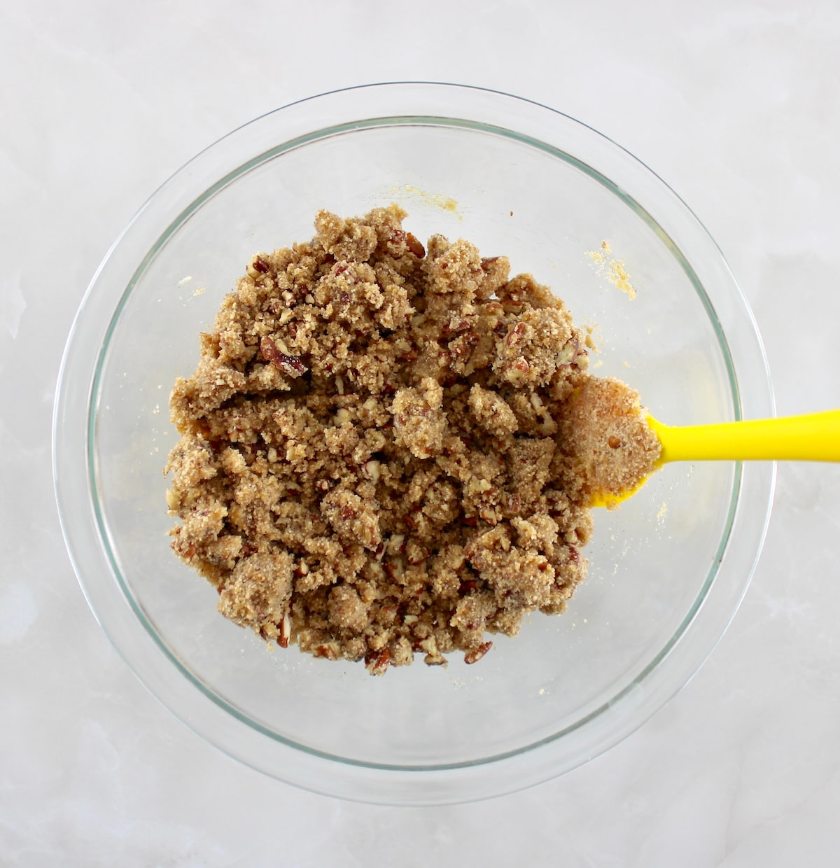 Pumpkin Casserole streusel topping in glass bowl with yellow spoon